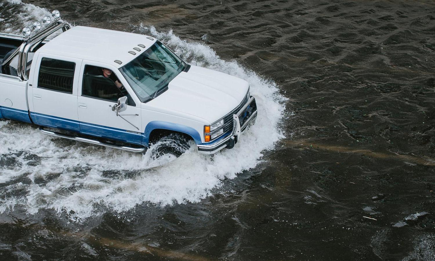 A truck drives through flooded water.