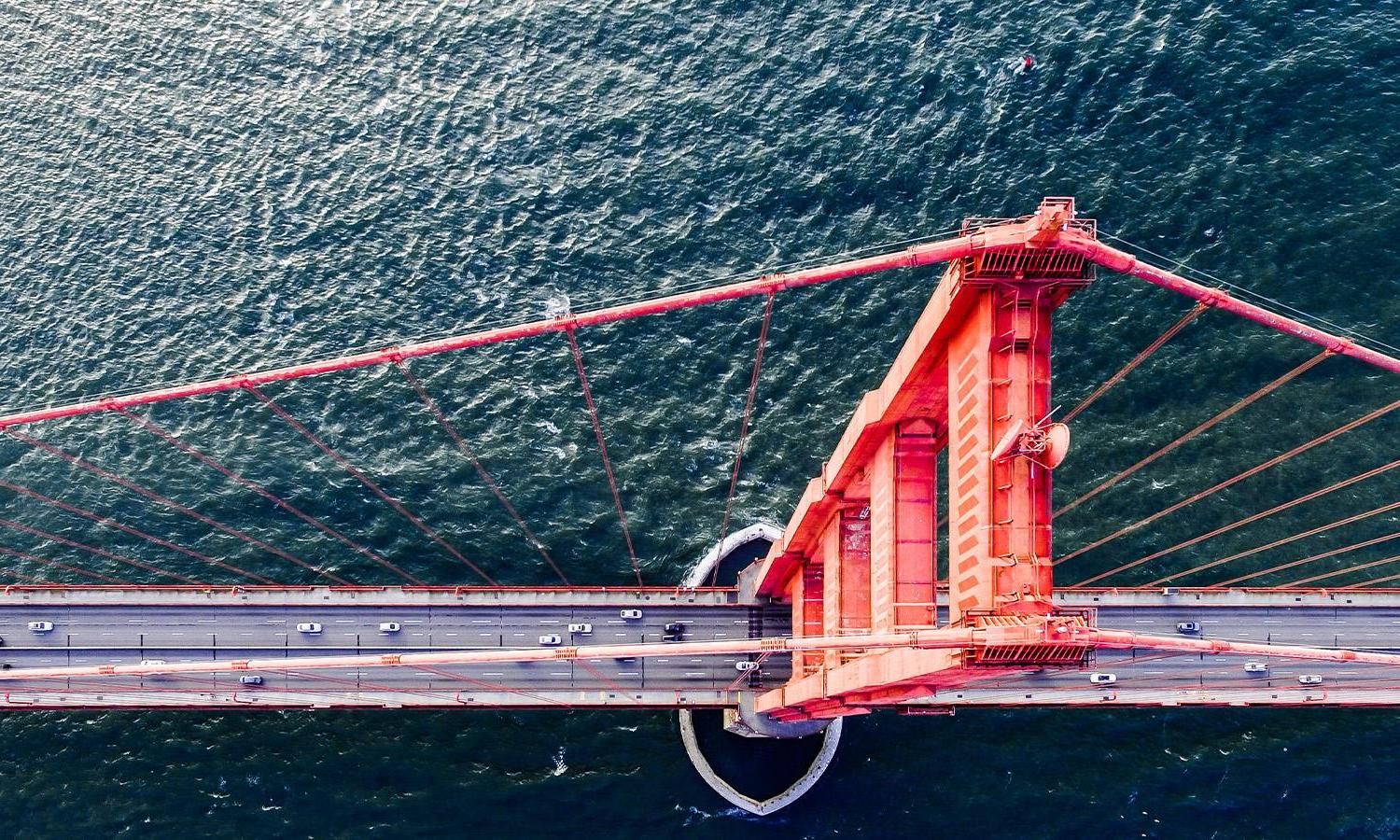 An aerial view of cars driving over the Golden Gate bridge. 
