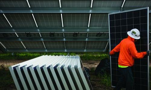 A worker carries a solar panel