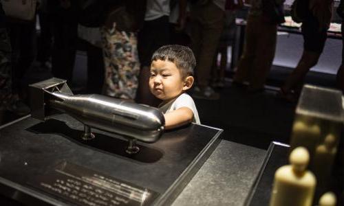 Boy looking at model of atomic bomb model, "little boy" used in WWII